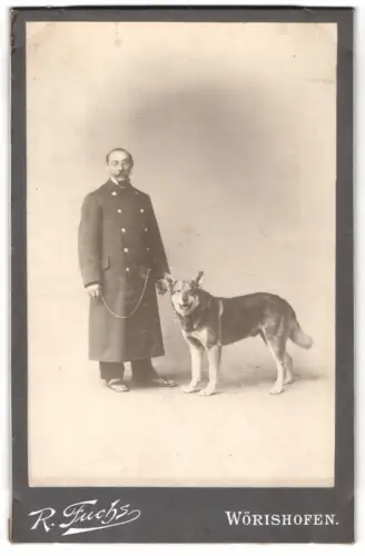 Fotografie R. Fuchs, Wörishofen, Beamter im Mantel mit seinem Diensthund an der Kette, Mann trägt Latschen