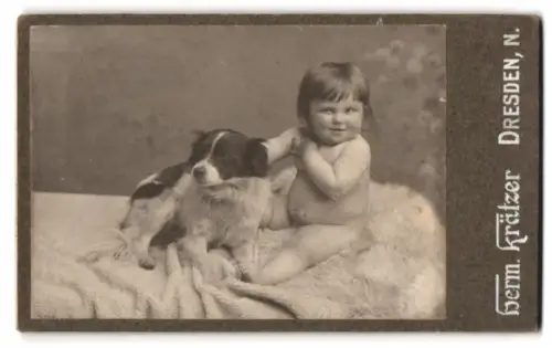 Fotografie Herm. Krätzer, Dresden, kleines Kind mit seinem Hund auf einer Felldecke