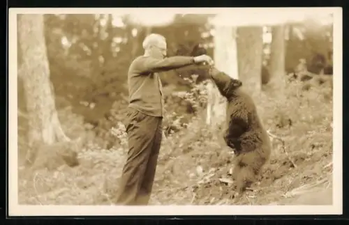 AK Mann füttert einen jungen Bären mit der Hand