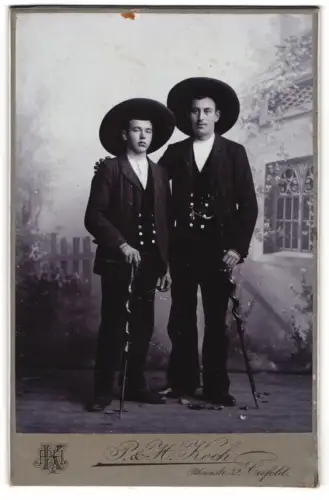 Fotografie P. & H. Koch, Crefeld, ziwe junge Handwerker / Zimmermänner auf der Walz mit Knotenstock, Zimmermannskluft