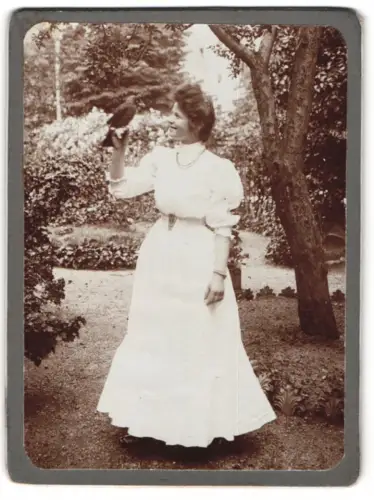Fotografie junge Frau mit einer Dohle / Vogel auf der Hand im Garten