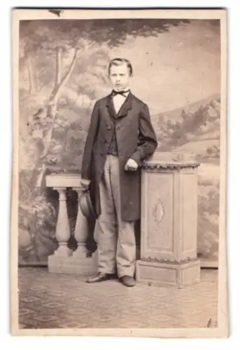 Fotografie unbekannter Fotograf und Ort, junger Mann im Anzug vor einer Studiokulisse