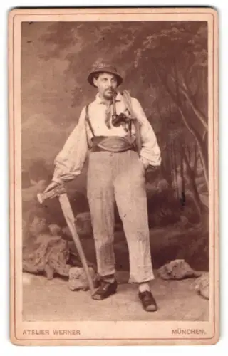 Fotografie Atelier Werner, München, junger Mann als Holzknecht mit Axt und Pfeife in Tracht