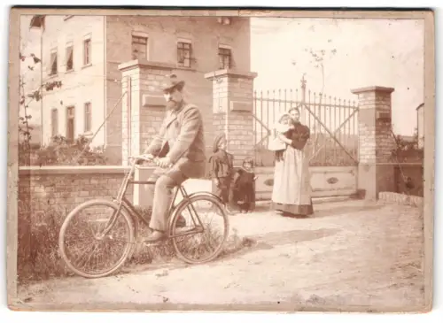 Fotografie unbekannter Fotograf und Ort, Vater auf Fahrrad und Familie vor Tor, Familie Amedick