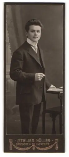 Fotografie Atelier Müller, Bärenstein, Stehender Mann neben Tisch