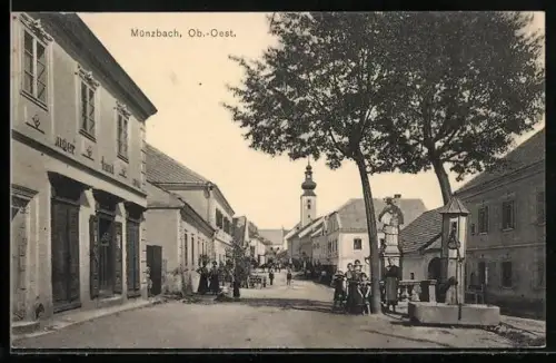 AK Münzbach /O.-Oe., belebte Strassenpartie mit Brunnen