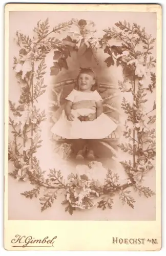 Fotografie H. Gimbel, Hoechst a/M, Königsteinerstr. 17, Porträt eines lächelnden Kindes in blumigem Rahmen, Passepartout