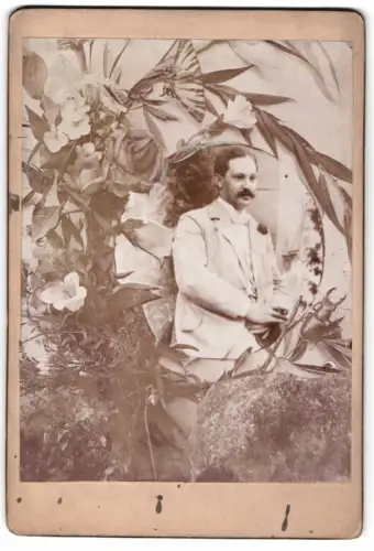 Fotografie unbekannter Fotograf und Ort, Mann mit floralem Hintergrund im Passepartout
