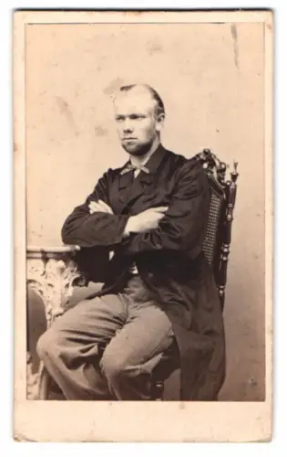 Fotografie H. Hagemeister, Schwerin, Sitzender Mann mit verschränkten Armen