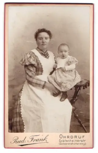 Fotografie Rud. Frank, Ohrdruf, Gräfenheinerstr, Amme mit Kind im Arm auf einem Stuhl sitzend
