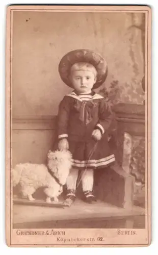 Fotografie Grundner & Abich, Berlin, Köpenickerstr. 62, Kind mit Spielzeugschaf auf Rollbrett