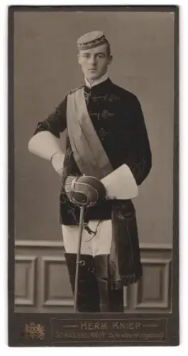 Fotografie Herm. Kniep, Strassburg i. E., Schreibergasse 6, Student Hans Reisch im vollen Wichs mit Schläger, 1910