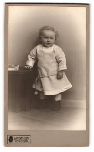 Fotografie A. Wertheim, Berlin, Königstr., Kleinkind steht neben Tisch