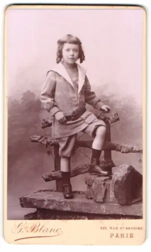 Fotografie G. Blanc, Paris, Rue St. Antoine 222, Kind vor einem rustikalen Zaun im Atelier