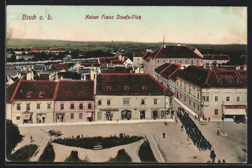 AK Bruck a. L., Kaiser-Josefs-Platz aus der Vogelschau, mit Geschäften und Militär-Aufzug