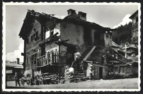 AK Saint-Luc, Mann trägt schweren Sack ins Haus