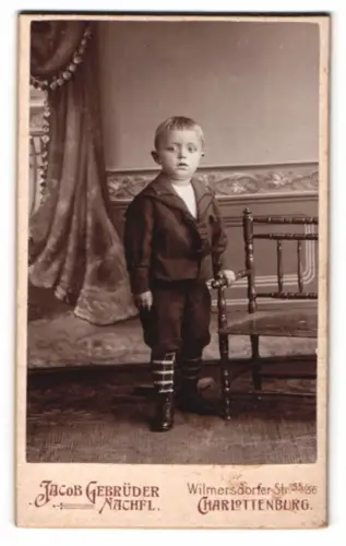 Fotografie Jacob Gebrüder Nachfl., Charlottenburg, Wilmersdorfer Str. 55/56, Kleiner Junge neben Stuhl