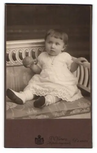 Fotografie P. Clasen, Dessau, Kind auf Sofa mit Spielzeug