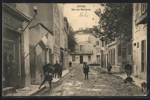 AK Istres, Rue des Martigues animée avec des enfants et un drapeau francais