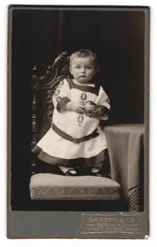 Fotografie Samson & Co., Berlin, Thurmstrasse 76, Kind auf gepolstertem Stuhl