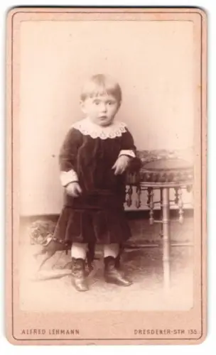 Fotografie Alfred Lehmann, Berlin, Dresdener-Str. 135, Kind in dunklem Kleid neben Tisch