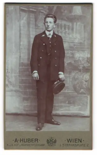 Fotografie A. Huber, Wien, junger Page in Uniform vor einer Studiokulisse