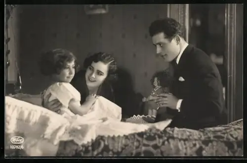 AK Junges Elternpaar zeigt Kind im Bett eine Puppe