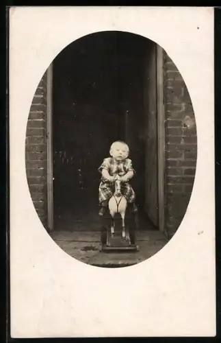 Foto-AK Kleines Kind auf Schaukelpferd vor einer Tür