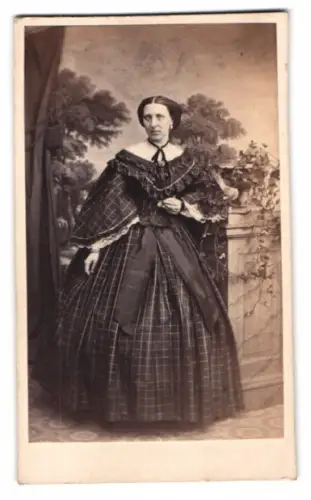 Fotografie J. G. Rost, Magdeburg, Dame im karierten Kleid posiert vor einer Studiokulisse