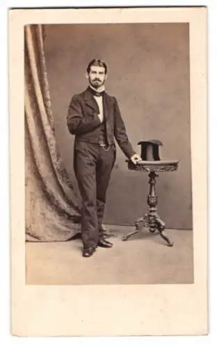 Fotografie G. Völkerling, Dessau, junger Mann im Frack mit Zylinder auf dem Tisch, Mann in Amerika verschollen