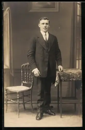 Foto-AK Eleganter Herr am Tisch in einer Studiokulisse