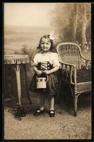 Foto-AK Kleines Mädchen am Korbstuhl in einer Studiokulisse