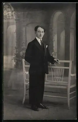Foto-AK Eleganter Herr raucht in einer Studiokulisse