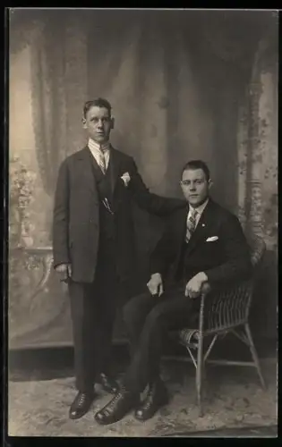 Foto-AK Zwei elegante Herren am Korbstuhl in einer Studiokulisse
