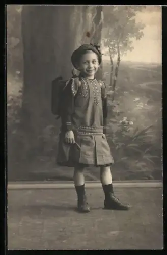 Foto-AK Mädchen im Kleid mit Schulranzen in einer Studiokulisse