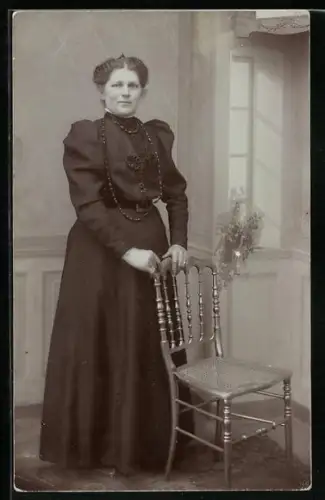 Foto-AK Frau im Kleid am Stuhl in einer Studiokulisse