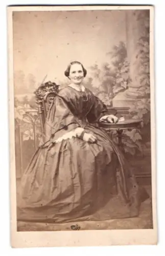 Fotografie Julius Becker, Magdeburg, Dame im Biedermeierkleid sitzend am Tisch