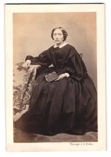 Fotografie Louis Gothe, Magdeburg, junge Frau im dunklen Kleid mit Album in der Hand