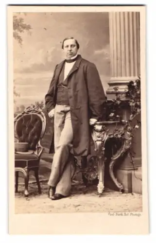 Fotografie Carl Suck, Berlin, Herr im feinen Anzug posiert vor einer Studiokulisse