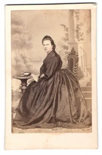 Fotografie attraktive junge Frau posiert sitzend vor einer Studiokulisse