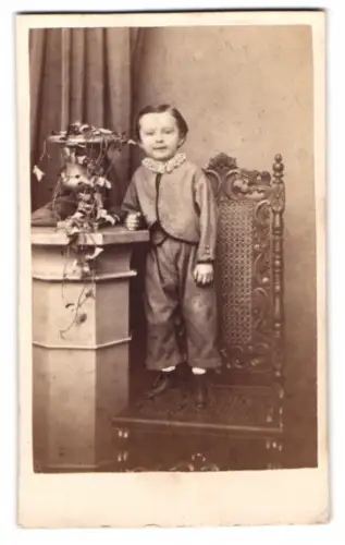 Fotografie J. Seboldt, Breslau, junger Knabe im grauen Anzug stehend auf einem Stuhl
