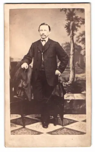 Fotografie H. Meyer, Berlin, Grosse Frankfurter Str. 117, eleganter Herr mit Jacke und Schirm vor einer Studiokulisse