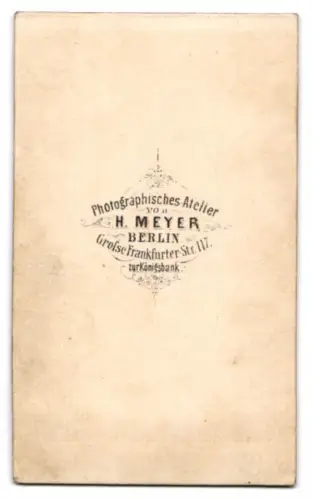 Fotografie H. Meyer, Berlin, Grosse Frankfurter Str. 117, eleganter Herr mit Jacke und Schirm vor einer Studiokulisse