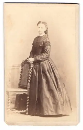 Fotografie unbekannter Fotograf und Ort, junge Frau im eleganten Kleid an Stuhl gelehnt