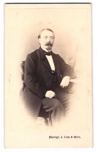 Fotografie Lutze & Witte, Stettin, Kleine Dom-Strasse, Porträt eines sitzenden Mannes mit Mustasch