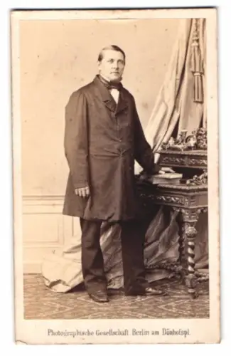 Fotografie Photographische Gesellschaft, Berlin am Dönhofsplatz, Herr in Anzug neben Tisch