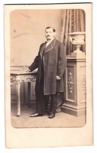 Fotografie E. Herold & Riemann, Breslau, Zwinger Str. 4, Stehender Herr neben kunstvoll verziertem Tisch