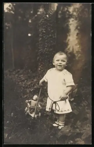 AK Kind zieht eine Puppe in einem Wagen hinter sich her