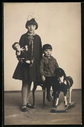 Foto-AK Mädchen mit Puppe und Junge mit Schaukelpferd
