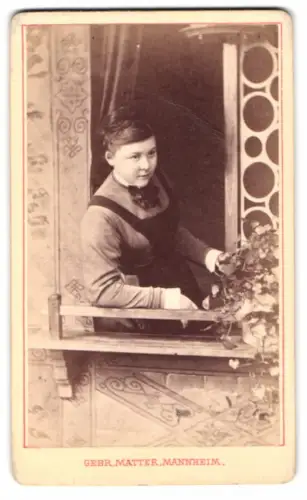 Fotografie Gebr. Matter, Mannheim, junge Hausfrau mit Schürze schaut aus dem Fenster einer Studiokulisse